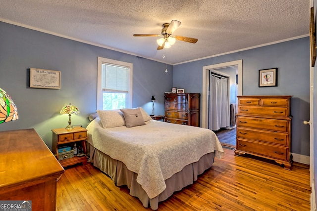 bedroom with a textured ceiling, hardwood / wood-style flooring, ceiling fan, and crown molding