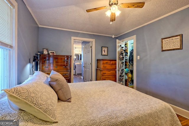 bedroom with a walk in closet, ensuite bathroom, ceiling fan, and crown molding