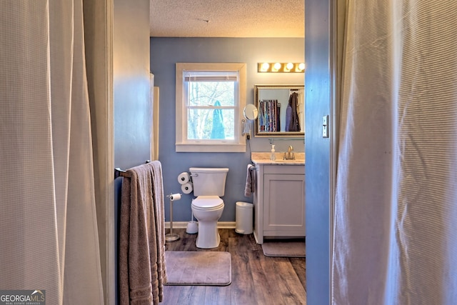 bathroom with hardwood / wood-style flooring, vanity, toilet, and a textured ceiling