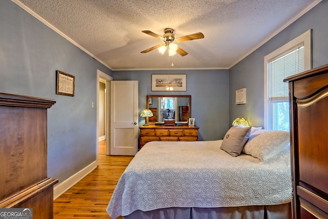 bedroom with ceiling fan, crown molding, light hardwood / wood-style floors, and a textured ceiling