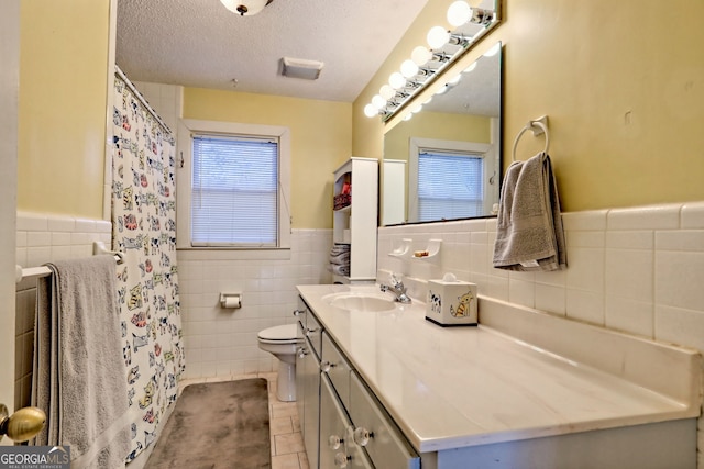 bathroom featuring vanity, a textured ceiling, tile walls, tile patterned flooring, and toilet