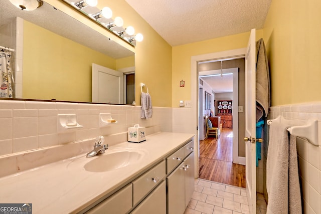 bathroom featuring tile patterned floors, vanity, a textured ceiling, and tile walls