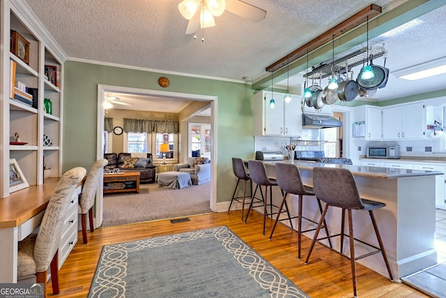 kitchen with white cabinets, a kitchen breakfast bar, light hardwood / wood-style floors, and tasteful backsplash