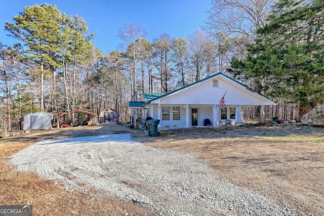 view of front facade featuring covered porch, a carport, and a storage shed