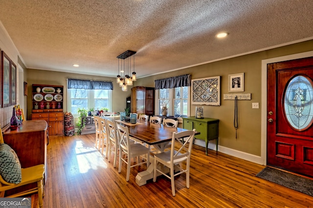 dining space featuring hardwood / wood-style floors, ornamental molding, a textured ceiling, and a chandelier