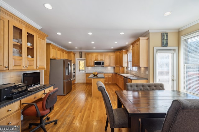 dining space featuring light wood-type flooring, sink, and ornamental molding