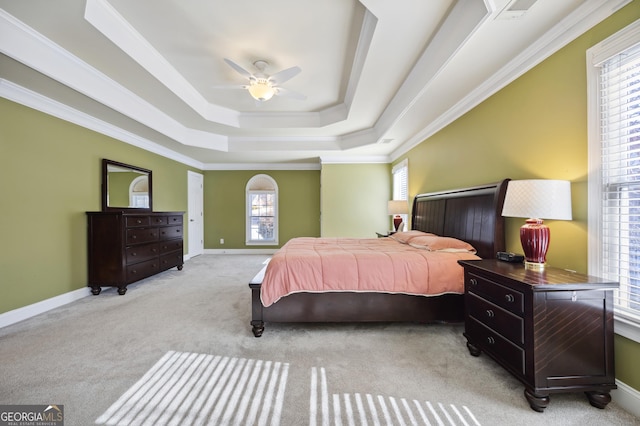 carpeted bedroom with a tray ceiling, ceiling fan, and ornamental molding