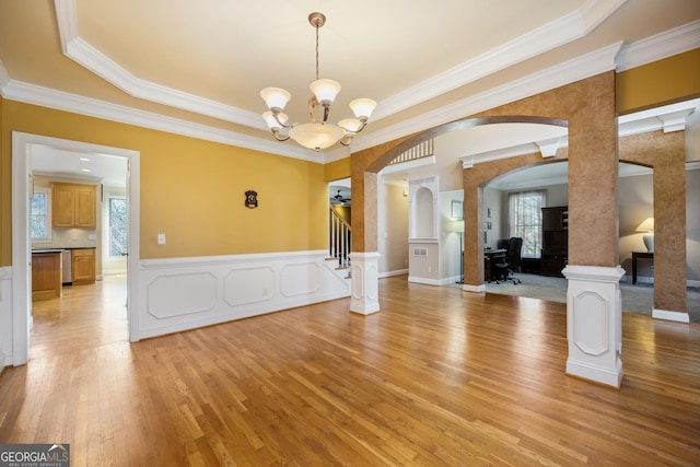 unfurnished dining area with ornate columns, an inviting chandelier, light hardwood / wood-style flooring, plenty of natural light, and ornamental molding