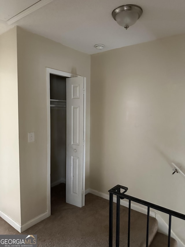 unfurnished bedroom with dark colored carpet, a closet, and baseboards