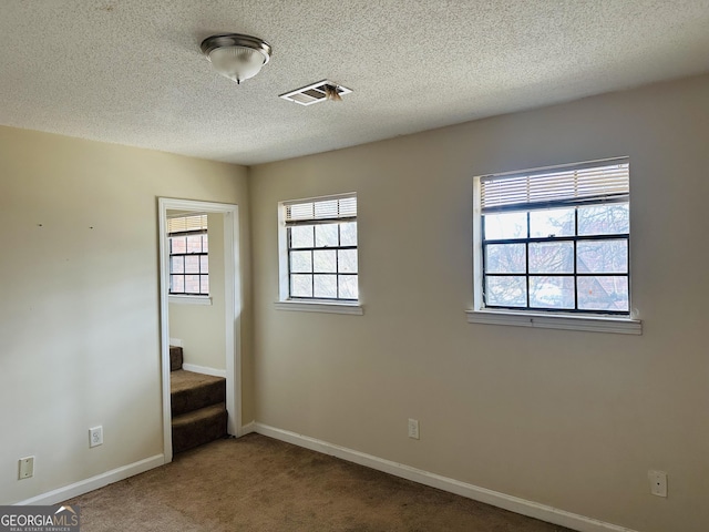 unfurnished bedroom with carpet floors, baseboards, visible vents, and a textured ceiling