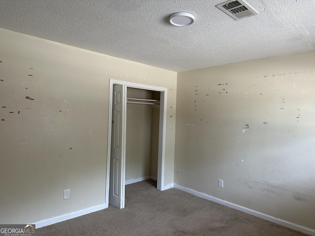 unfurnished bedroom with baseboards, visible vents, a textured ceiling, carpet floors, and a closet