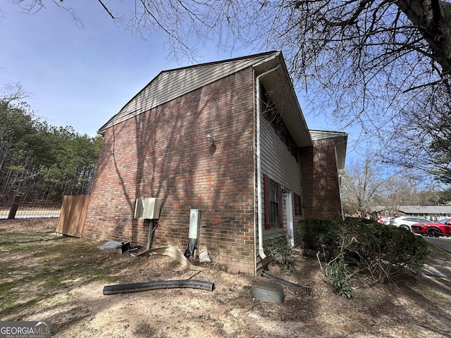 view of side of property featuring brick siding and fence