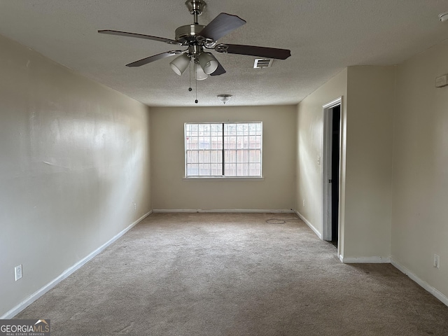 empty room featuring light colored carpet, visible vents, ceiling fan, a textured ceiling, and baseboards