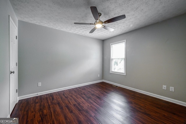 spare room with a textured ceiling, ceiling fan, and dark wood-type flooring