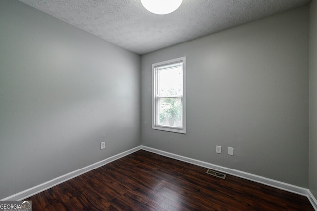 unfurnished room featuring a textured ceiling and dark hardwood / wood-style flooring