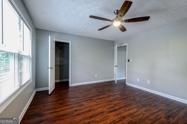 unfurnished bedroom with ceiling fan, dark hardwood / wood-style floors, and a textured ceiling