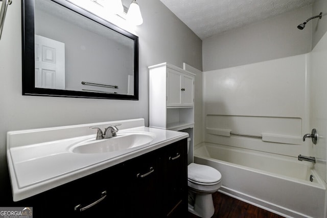 full bathroom featuring vanity, a textured ceiling, wood-type flooring, washtub / shower combination, and toilet