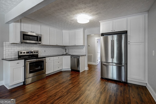 kitchen with backsplash, stainless steel appliances, dark wood-type flooring, sink, and white cabinetry