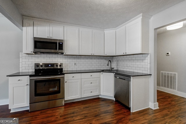 kitchen featuring white cabinetry, sink, stainless steel appliances, dark hardwood / wood-style floors, and backsplash