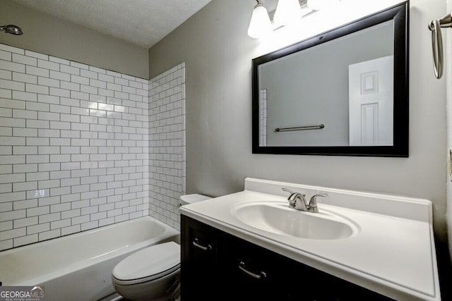 full bathroom with toilet, vanity, a textured ceiling, and tiled shower / bath combo