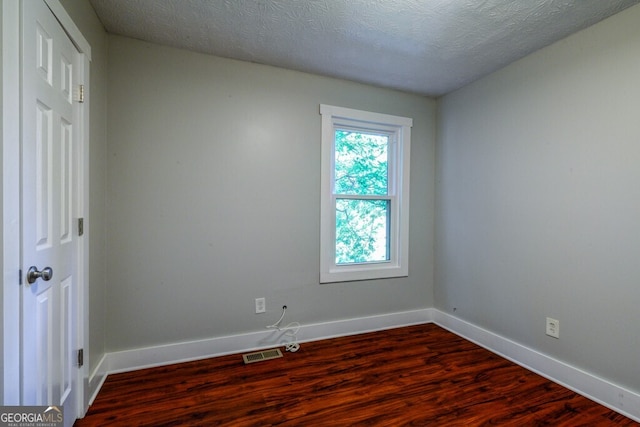 spare room featuring hardwood / wood-style floors and a textured ceiling