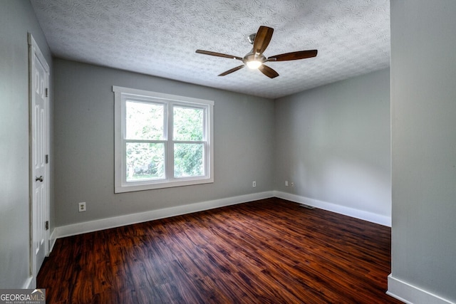 empty room with ceiling fan, dark hardwood / wood-style flooring, and a textured ceiling