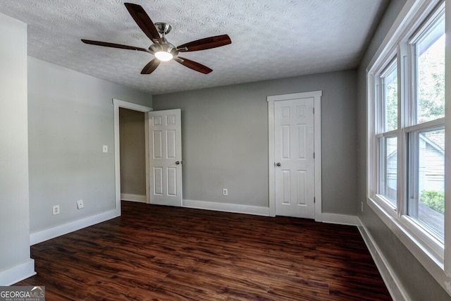 unfurnished room featuring a textured ceiling, ceiling fan, and dark wood-type flooring