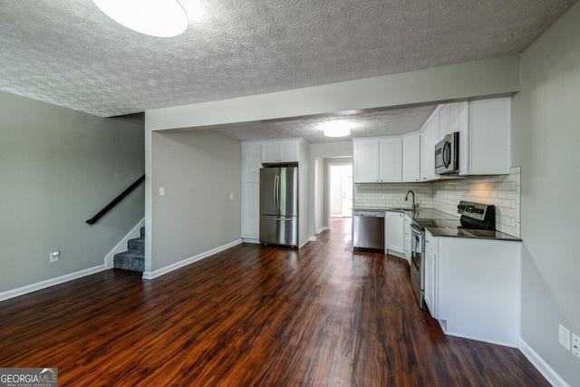 kitchen featuring white cabinetry, sink, dark wood-type flooring, stainless steel appliances, and backsplash