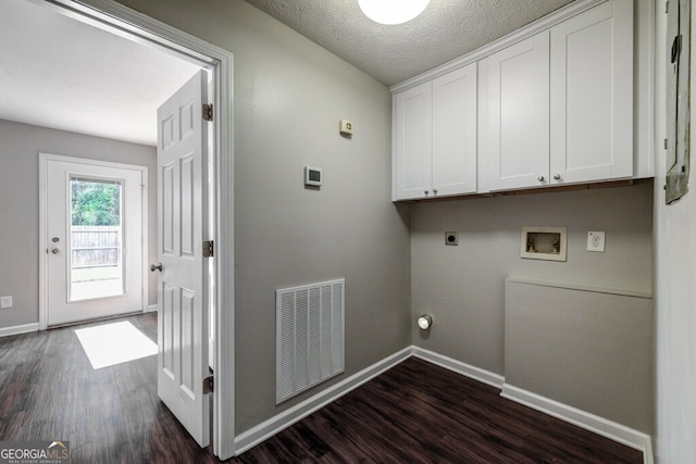 laundry room featuring electric dryer hookup, cabinets, hookup for a washing machine, dark hardwood / wood-style floors, and a textured ceiling