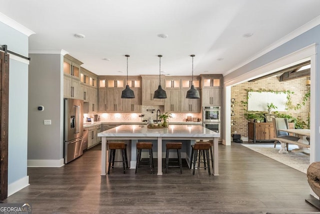 kitchen with hanging light fixtures, a barn door, appliances with stainless steel finishes, tasteful backsplash, and a large island