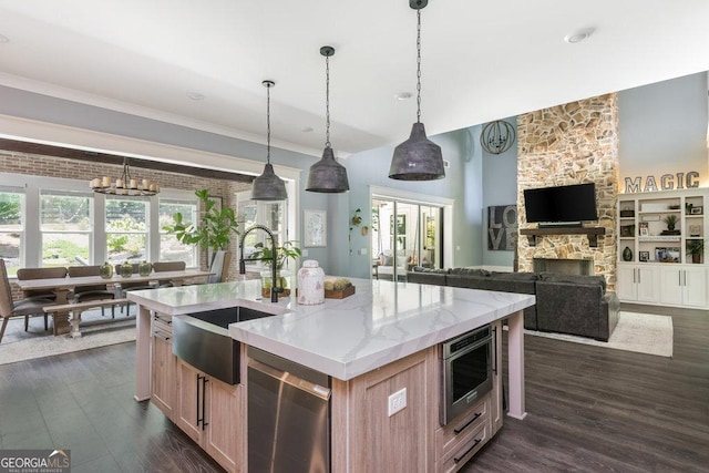 kitchen with a center island with sink, pendant lighting, sink, and a fireplace