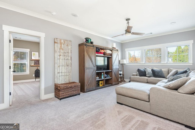 living room featuring a barn door, light colored carpet, ceiling fan, and ornamental molding