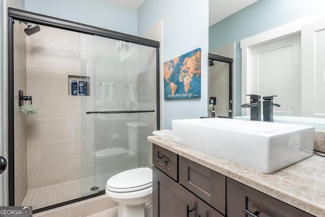 bathroom featuring vanity, toilet, and a shower with door