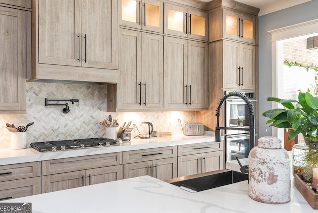 kitchen with tasteful backsplash, light brown cabinetry, sink, and stainless steel gas stovetop