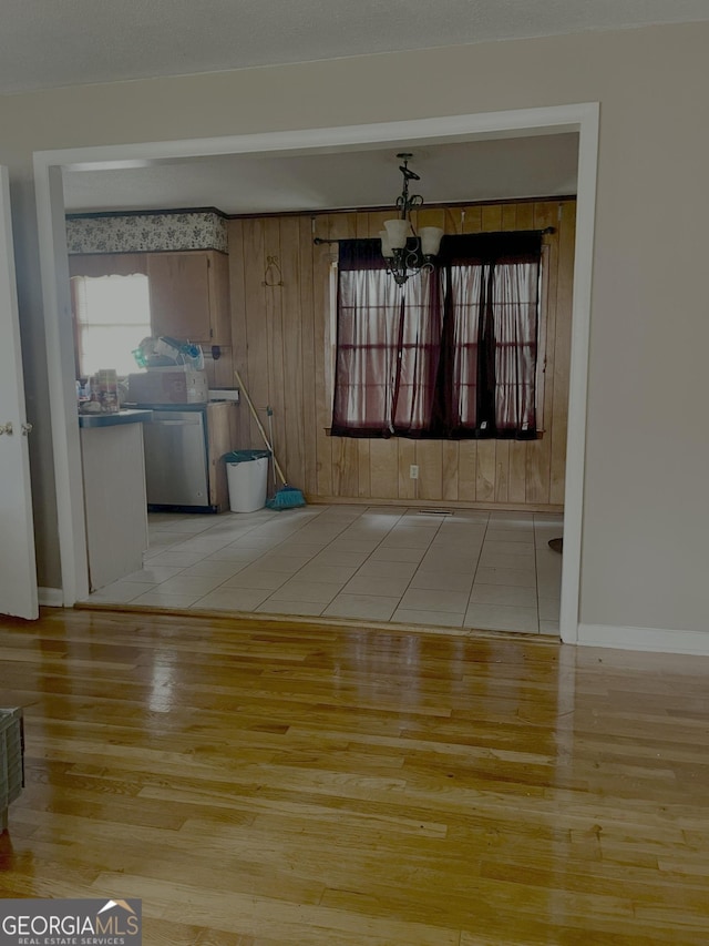 unfurnished dining area with light tile patterned floors and a notable chandelier