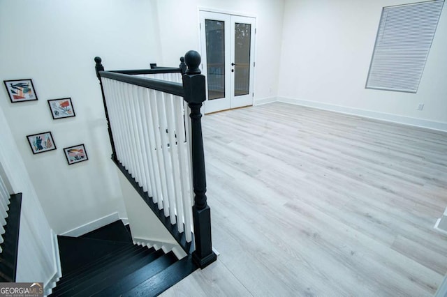 staircase with hardwood / wood-style floors and french doors