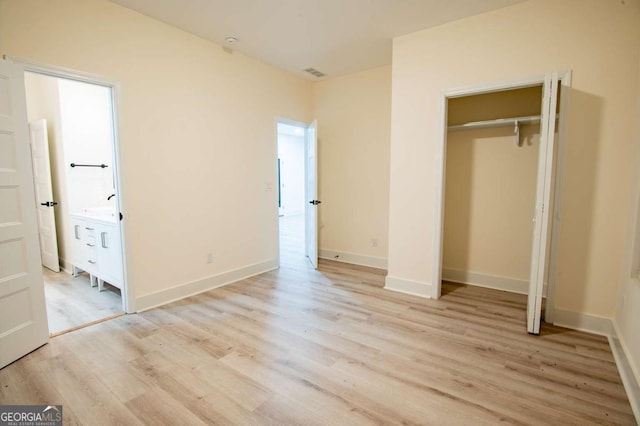 unfurnished bedroom with light hardwood / wood-style floors, ensuite bath, and a closet