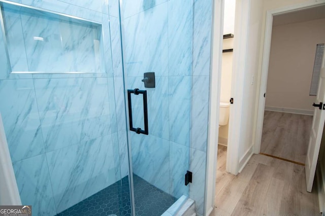 bathroom with toilet, wood-type flooring, and walk in shower