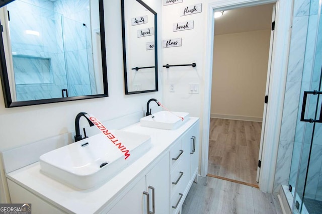 bathroom with hardwood / wood-style floors, vanity, and a shower with door