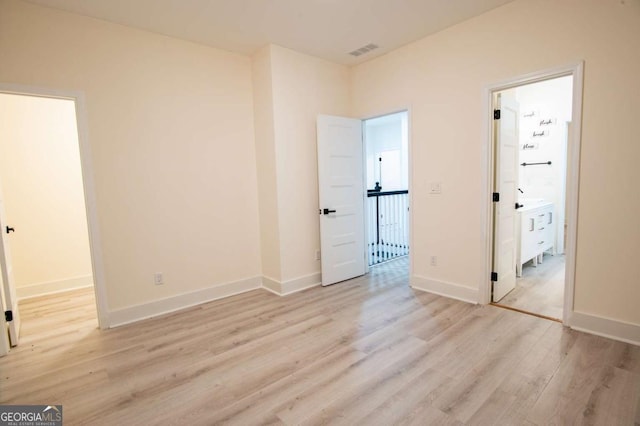 unfurnished bedroom with connected bathroom, light hardwood / wood-style floors, and a closet