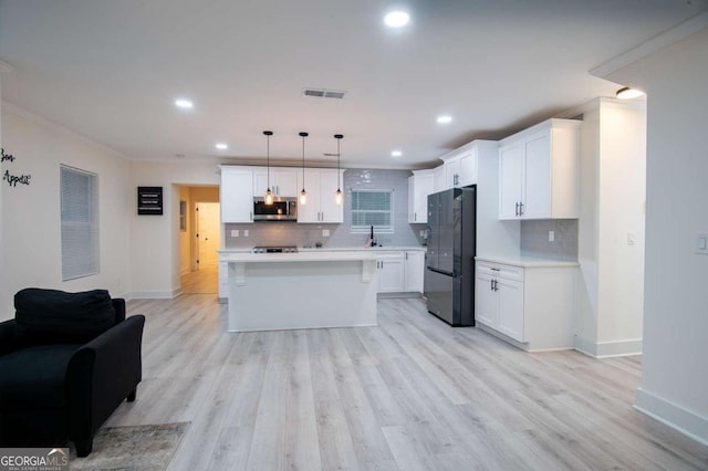 kitchen featuring black refrigerator, crown molding, decorative light fixtures, a kitchen island, and white cabinetry