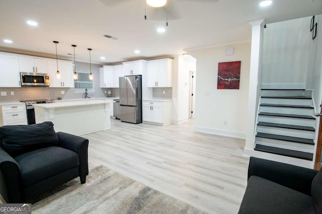 living room with ceiling fan, crown molding, light wood-type flooring, and sink