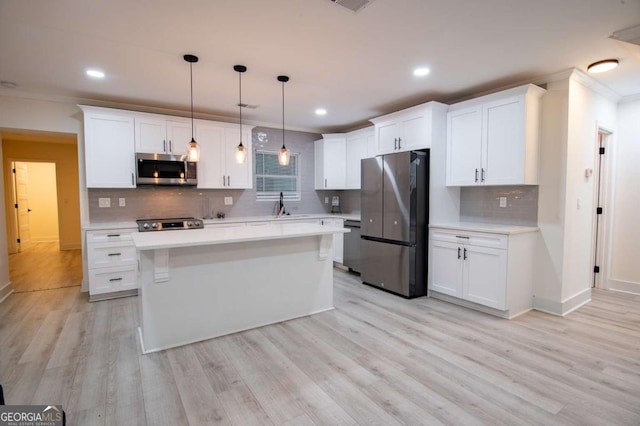 kitchen with white cabinets, appliances with stainless steel finishes, a kitchen island, and hanging light fixtures