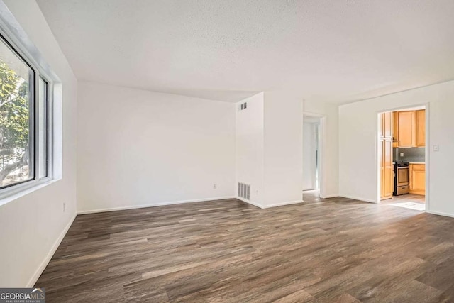 unfurnished room with a textured ceiling and dark wood-type flooring