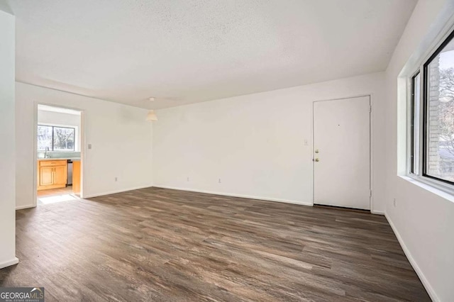 unfurnished room featuring a textured ceiling, dark hardwood / wood-style flooring, and a wealth of natural light