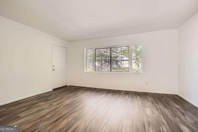 empty room with a textured ceiling and dark hardwood / wood-style flooring