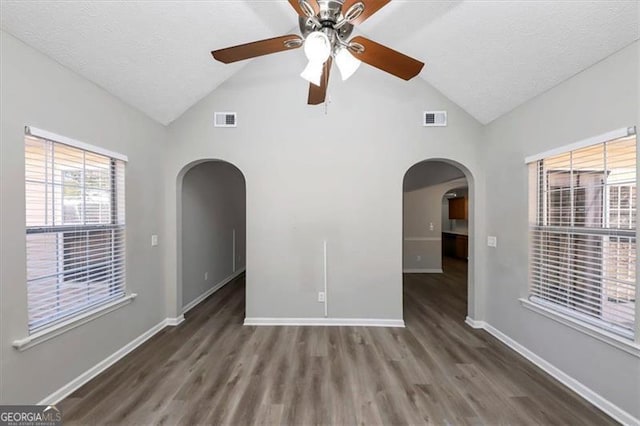 unfurnished room with a textured ceiling, ceiling fan, dark hardwood / wood-style floors, and vaulted ceiling