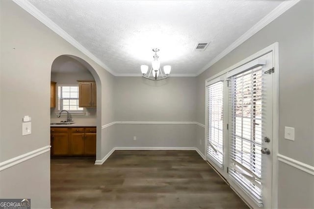 unfurnished dining area featuring crown molding, dark hardwood / wood-style flooring, sink, and a chandelier