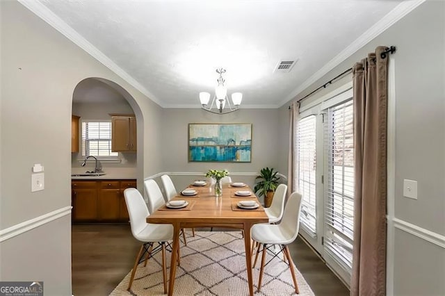 dining space featuring hardwood / wood-style flooring, a notable chandelier, crown molding, and sink