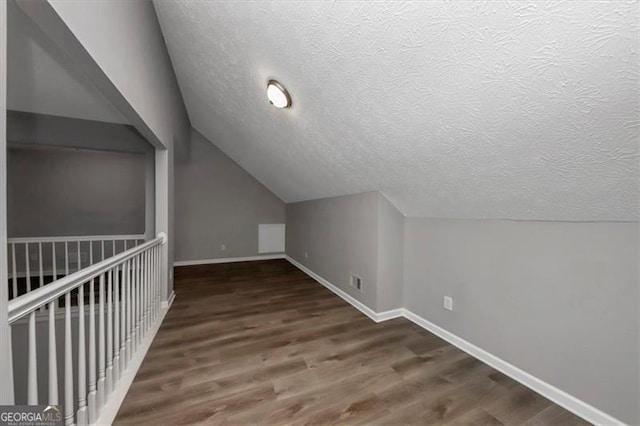 bonus room featuring dark hardwood / wood-style floors, lofted ceiling, and a textured ceiling